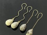 boucles d'oreilles pendantes à trois pierres, avec des chaînes dorées, sur un fond noir