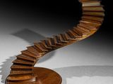 sculpture of a spiral staircase made of books on a wooden base