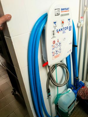 un tuyau bleu fixé au mur à côté des toilettes