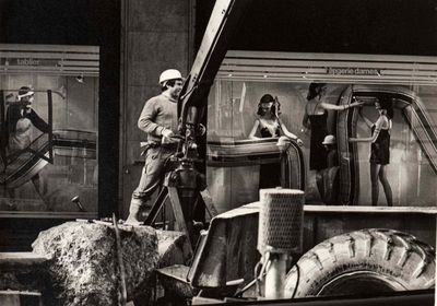 black and white photograph of a man standing on a truck with a crane
