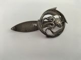 a silver spoon with a flower on it on a white surface