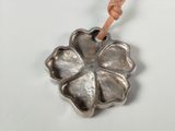 silver flower pendant with leather cord on a white surface