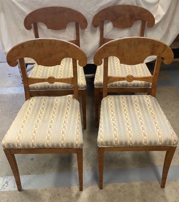 two wooden chairs with upholstered seats in front of a white curtain