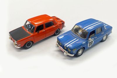 two toy cars sitting next to each other on a white surface