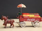 a toy horse pulling a coca cola cart with a man on it
