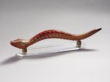 une sculpture en verre représentant un serpent, posée sur un socle transparent