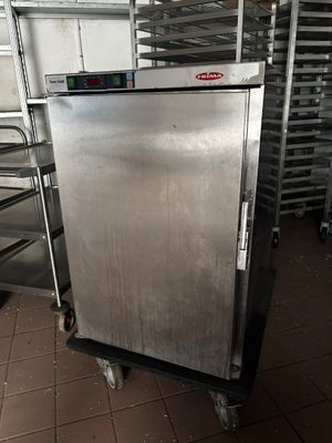 un réfrigérateur argenté posé sur un chariot dans une cuisine