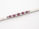 a close up of a bracelet with pink stones on a white surface