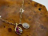 necklace with a gold chain and a red stone on a wooden board