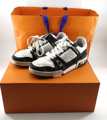 des baskets blanches et noires dans une boîte, sur fond blanc