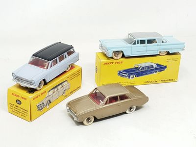 trois petites voitures sont posées sur des boîtes sur une surface blanche