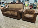 une paire de canapés Chesterfield en cuir marron dans un entrepôt