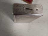 a silver lighter sitting on a table next to a red box