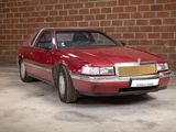 a red car that is parked in front of a brick wall