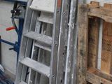 a ladder that is leaning against a wall next to a pile of pallets