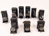 several old cameras are lined up in a row on a white surface