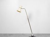 un lampadaire avec un pied en métal et un abat-jour blanc