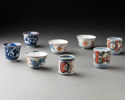 six petites tasses décorées sont posées sur une table
