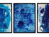 four blue abstract paintings hanging on a wall in a room