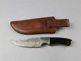 a knife that is laying next to a leather sheath