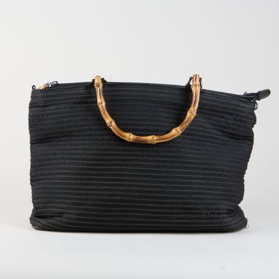 un sac noir tissé, muni de poignées en bambou et d'une poignée en bois