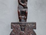a wooden statue of a person sitting on top of a vase