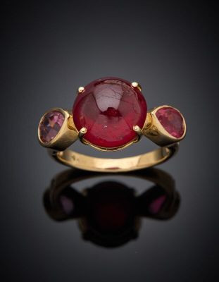 a close up of a gold ring with a ruby stone