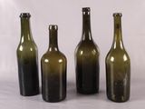 trois bouteilles de vin vides posées les unes à côté des autres sur une surface blanche