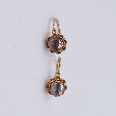 a pair of gold earrings with grey crystals on a white background