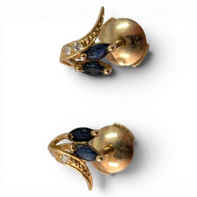 two pairs of gold and sapphire earrings on a white surface