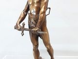 statue en bronze représentant un homme tenant une épée, exposée dans une vitrine transparente