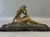 statue en bronze représentant une femme assise sur un socle en marbre