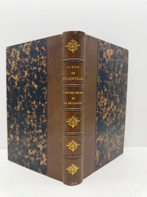 un vieux livre posé sur une table blanche à côté d'un mur blanc