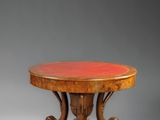 une table ronde avec un piètement en bois et un plateau rouge