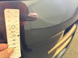 a person that is holding a ruler in front of a car