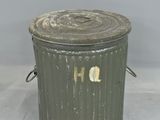 a green trash can with a hole in the lid