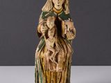 une vieille statue représentant une femme tenant un bébé et un chien dans ses bras