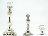 three silver candlesticks sitting next to each other on a table