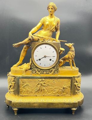 a gold clock with a statue of a woman sitting on top of it