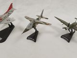 three model airplanes are lined up on a white surface