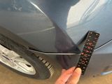 a person holding a ruler that is on the side of a car