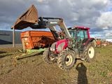 un tracteur qui est à l'arrêt dans la terre, près d'un camion-benne