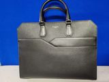 un sac à main noir posé sur une table avec un fond bleu