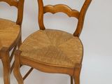 pair of wooden chairs with wicker seats against a white background