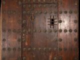 une vieille porte en bois avec des rivets métalliques et une petite fenêtre