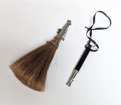 un gros plan montrant une paire de ciseaux et une brosse à cheveux posés sur une surface blanche