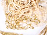 a pile of pearls and other jewelry on a white surface