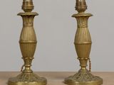 une paire de bougeoirs anciens en laiton posés sur une table en bois