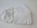 three pieces of white linen with lace on them sitting on a table