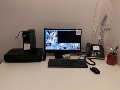 un bureau sur lequel se trouvent un ordinateur, un clavier, un téléphone et d'autres objets